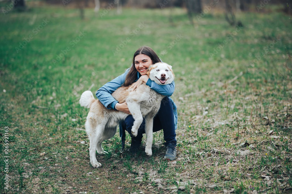 Young woman play with husky dog for a walk in spring forest. laughing having fun, happy with pet Young woman play with husky dog for a walk in spring forest. laughing having fun, happy with pet
