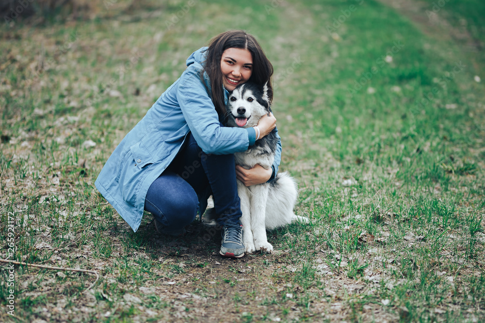 Young woman play with husky dog for a walk in spring forest. laughing having fun, happy with pet Young woman play with husky dog for a walk in spring forest. laughing having fun, happy with pet