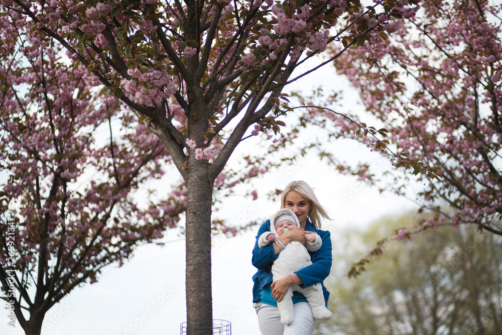 Young mother woman enjoying free time with her baby boy child - Caucasian white child with a parent's hand visible - Dressed in white overall with hearts, mom in blue Young mother woman enjoying free time with her baby boy child - Caucasian white child with a parent's hand visible - Dressed in white overall with hearts, mom in blue