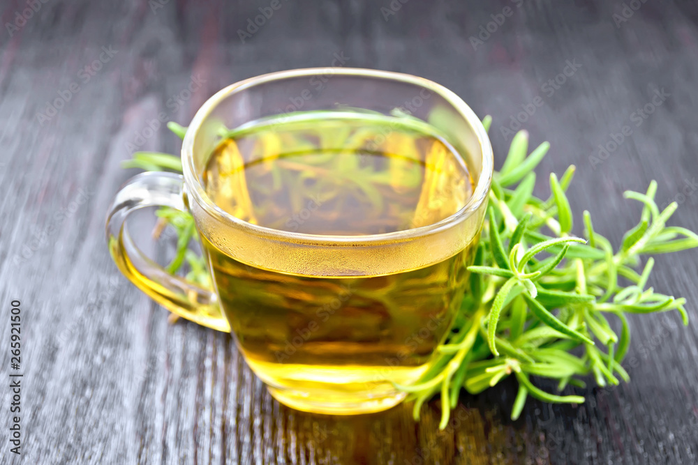 Tea of rosemary in cup on dark wooden board Tea of rosemary in cup on dark wooden board