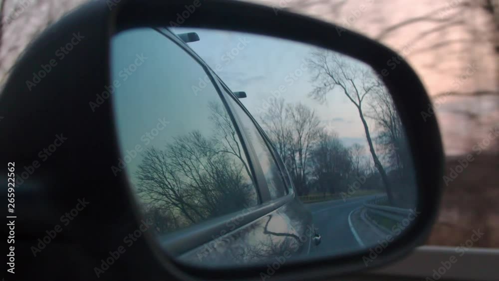 Side Mirror View of Car Driving by Trees and Houses Side Mirror View of Car Driving by Trees and Houses