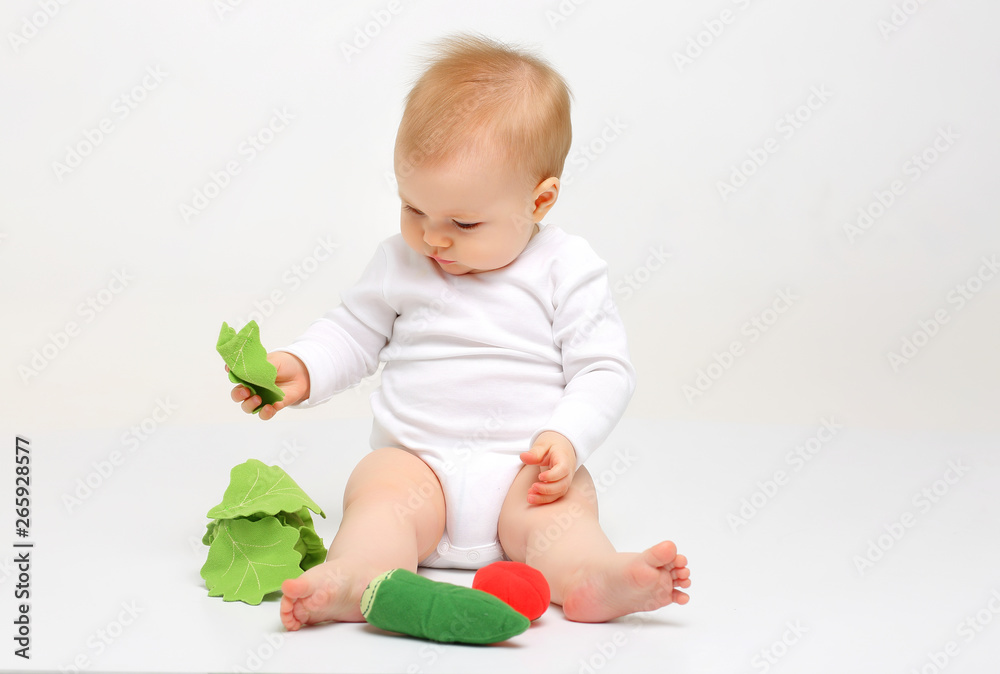 Charming blue-eyed baby sitting on a white background with colored educational toys Charming blue-eyed baby sitting on a white background with colored educational toys