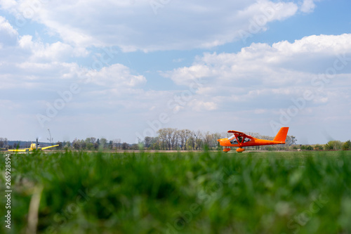 small red charter airplane waiting on a green field to take off