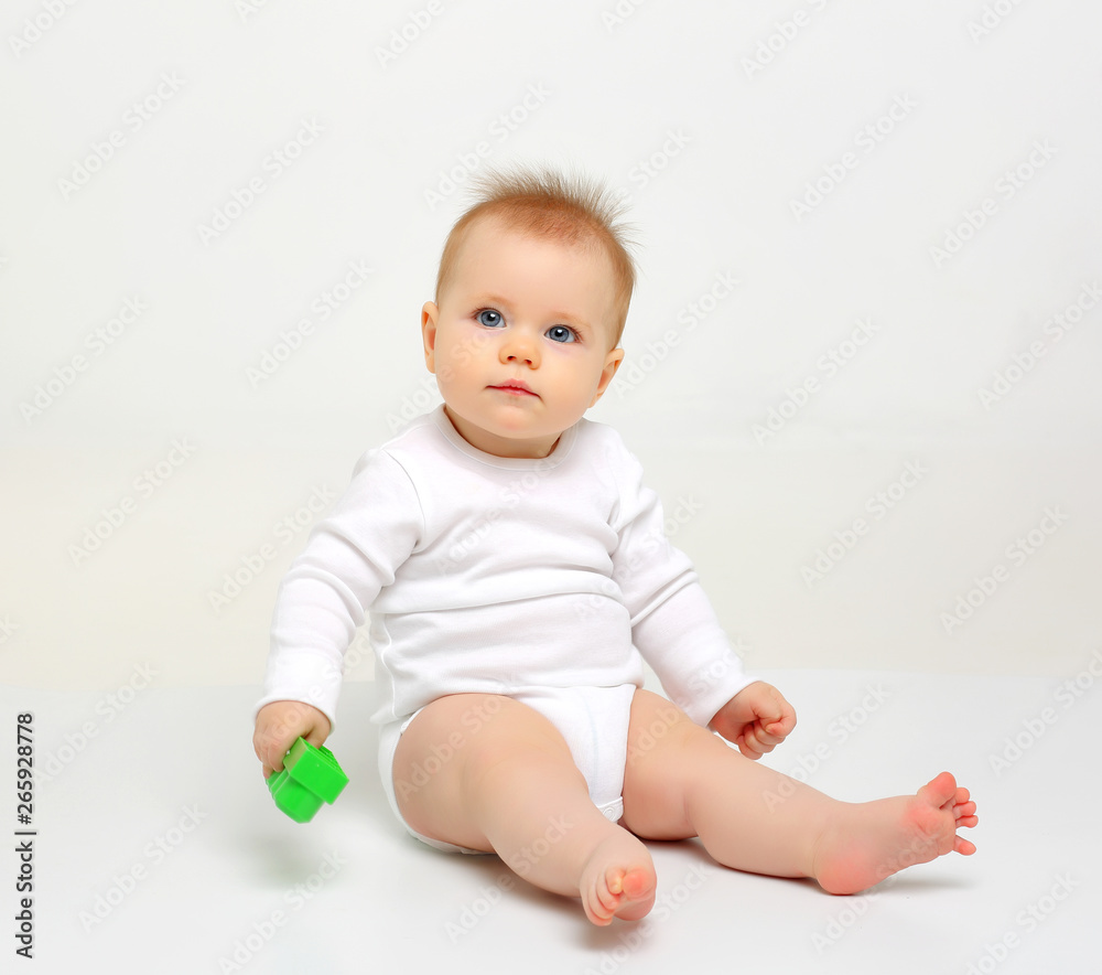 Charming blue-eyed baby sitting on a white background with colored educational toys Charming blue-eyed baby sitting on a white background with colored educational toys