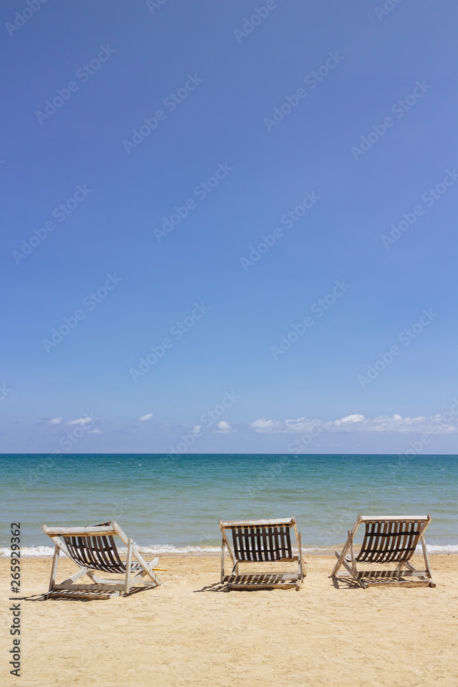 Three folding beach chairs on the beach with sea and bright sky in the background at Koh Mak in Trat, Thailand. Seasonal Vacation. Background with copy space.