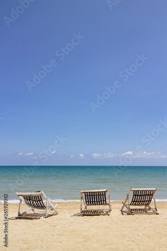 Three folding beach chairs on the beach with sea and bright sky in the background at Koh Mak in Trat  Thailand. Seasonal Vacation. Background with copy space.
