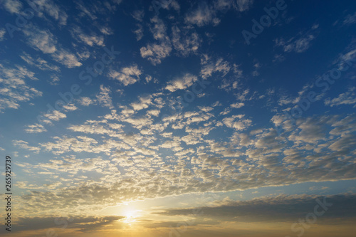 Rising sun over blue sky with cirrocumulus clouds