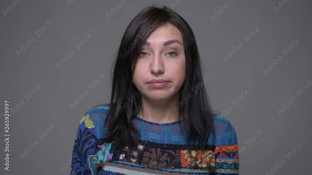 Closeup portrait of adult caucasian brunette female being irritated and angry looking at camera with background isolated on gray Closeup portrait of adult caucasian brunette female being irritated and angry looking at camera with background isolated on gray