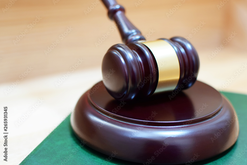 Judges gavel or mallet on green law book on wooden table. Legal law, justice system, education and judgement concept.
