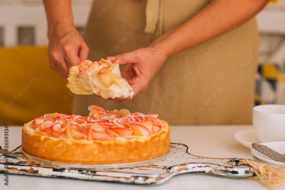 Woman's hand serving a slice of a freshly baked cake. Tasty homemade apple pie on white rustic table. Traditional american dessert. Bio healthy food. Tasty breakfast.