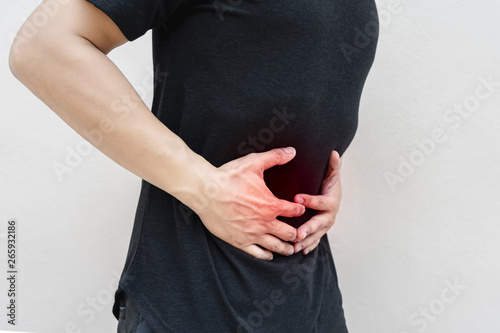 Young man holding his stomach in pain.