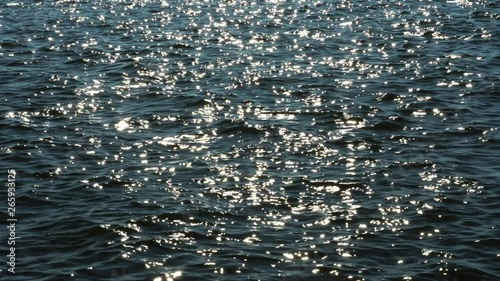 sparkling dark blue water at sunset, small waves are moving in the wind