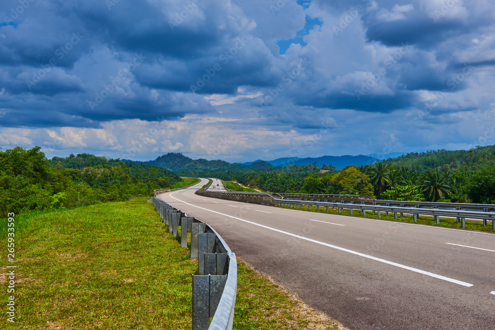 Road to the Cameron Highlands and hilly in haze landscape in the background. Concept of travel in Malaysia. Spectacular view a cloudy sky and lush tropical rainforest.
