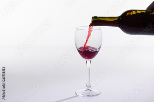 Pouring red wine into the glass on white background with copy space