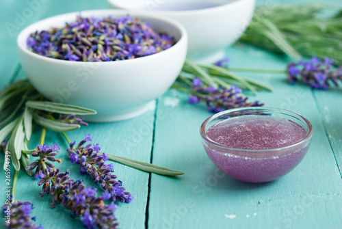 cup of lavender tea with a pile of fresh flowers  syrup  sugar candy on blue wood table background