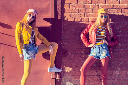 Two Girl Having Fun on Street. Outdoor Fashion. Carefree Woman posing near Brick Wall. Happy positive emotion. Pop Art. Stylish Hipster Friends in Creative Colorful Outfit, Sunglasses, funny concept