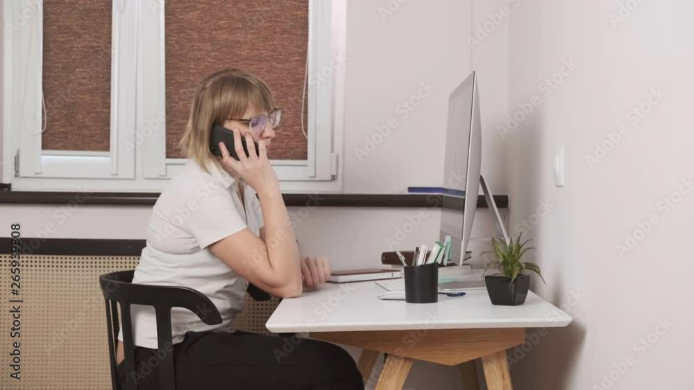 European blonde woman solves problems by phone at her workplace, close-up, business. European blonde woman solves problems by phone at her workplace, close-up, business.