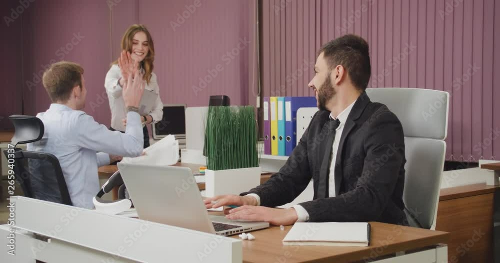 Young managers in a modern office, office workers on background, man throws up papers with documents, positive emotions, slow motion. Young managers in a modern office, office workers on background, man throws up papers with documents, positive emotions, slow motion.