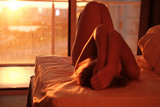 Portrait of blond girl with amazing body in hotel bed at sunset