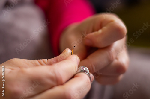 Woman cutting and knotting a thread on a needle