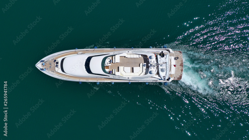 Aerial drone bird's eye top view photo of luxury yacht with wooden deck docked in deep blue waters of Mykonos island, Cyclades, Greece Aerial drone bird's eye top view photo of luxury yacht with wooden deck docked in deep blue waters of Mykonos island, Cyclades, Greece