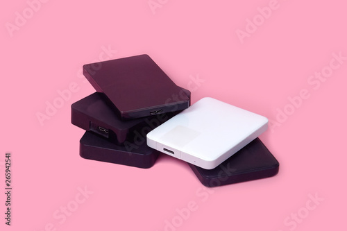 Some external hard drives for storing data, backups and security information. Pink background, isolated, copy space.