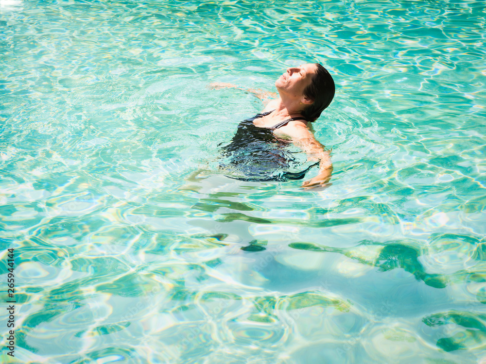 Woman lying on clear water at tropical beach. beautiful mature girl lying and enjoying in water and relaxing