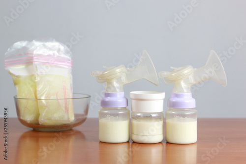 Bottles and frozen breast milk storage bags for new baby on wooden table