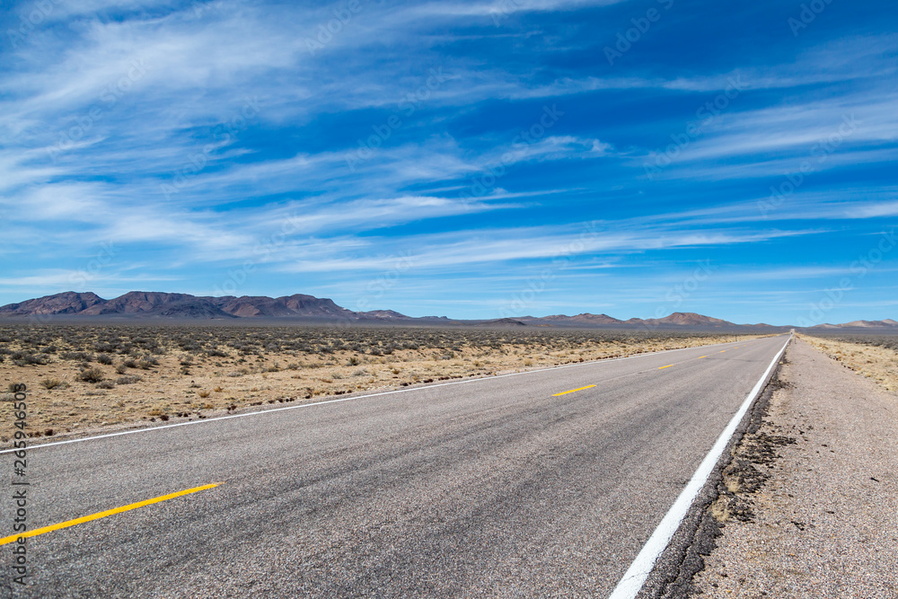 Looking along the Extraterrestrial Highway in Nevada, with a blue sky and wispy clouds overhead