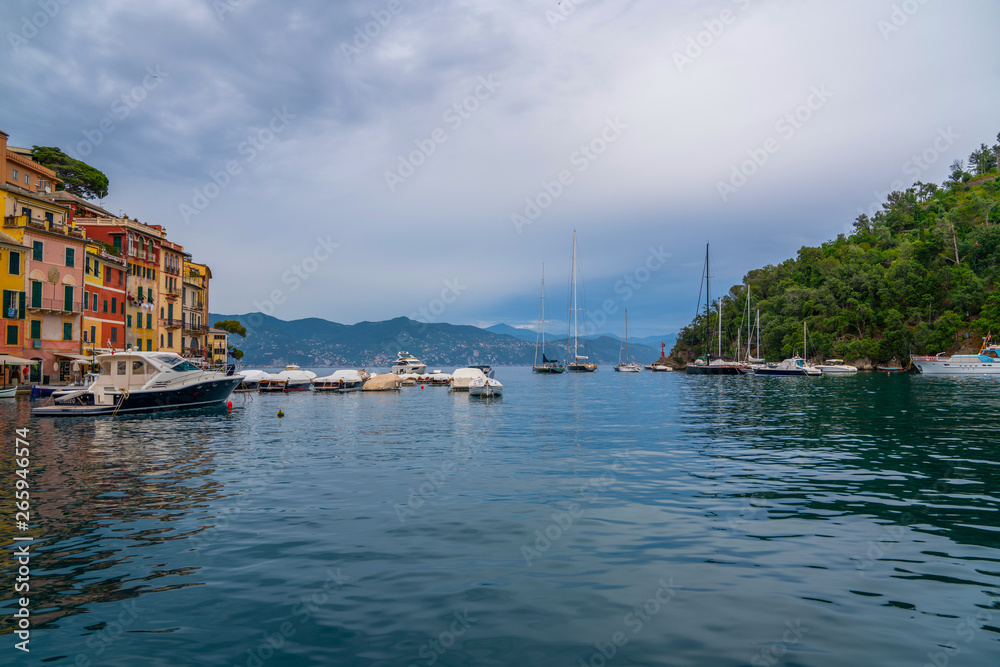 Sailboats at anchor in the entrance to the harbor. Amazing colorful mediterranean landscape, fantastic panorama of Portofino touristic village on Liguria coast, Italy, Europe.