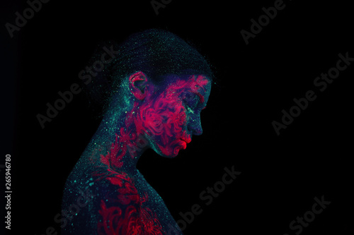 Profile portrait of a beautiful girl alien. Ultraviolet body art green night sky with stars and pink jellyfish. Head lowered