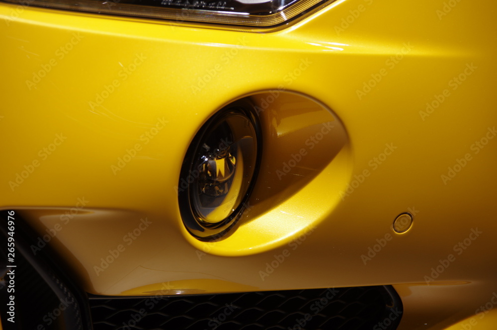 Yellow modern sports car round fog light close up view