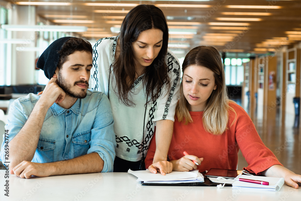 Group of young students studying together in library. Group of young students studying together in library.