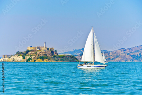 Photography View of Alcatraz Island with a sailboat passing by on San Francisco Bay in San Francisco