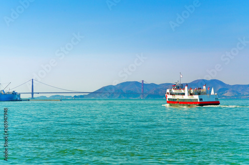 View of a ferry running on San Francisco Bay with Golden Gate Bridge in the background in San Francisco.