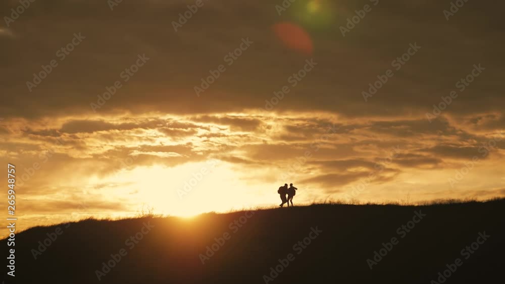 Couple hiking help each other silhouette in mountains. Teamwork couple hiking, help each other, trust assistance, sunset. Man giving hand a woman to help her to climb the mountain. Couple hiking help each other silhouette in mountains. Teamwork couple hiking, help each other, trust assistance, sunset. Man giving hand a woman to help her to climb the mountain.