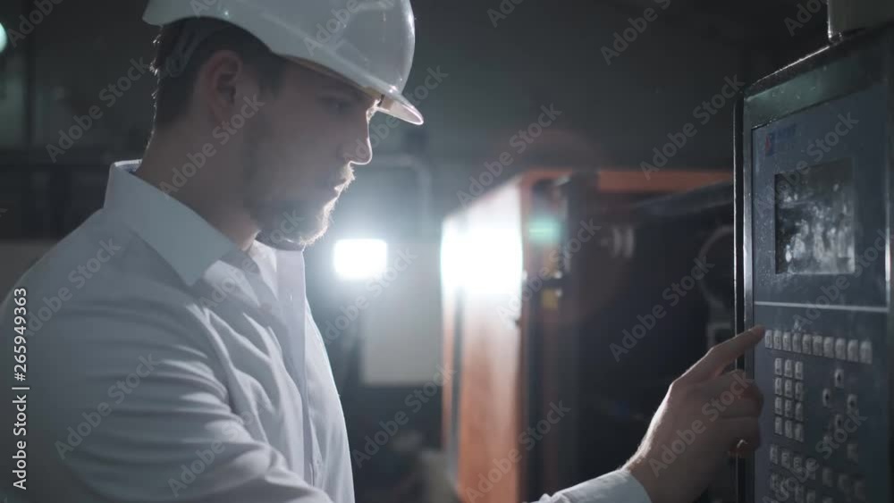 Young engineer in helmet controls the process on the factory . 4k