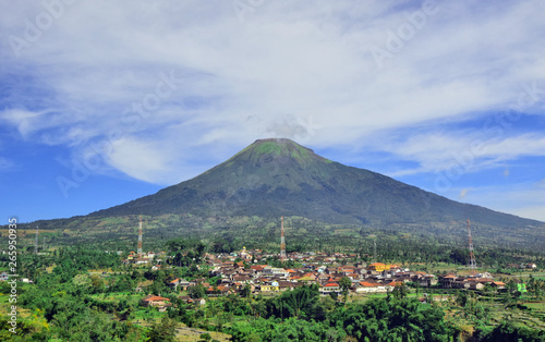 clean natural mountain scenery with bright blue sky with countryside below. This mountain is called "Mount Sindoro", which is in Temanggung, Central Java.