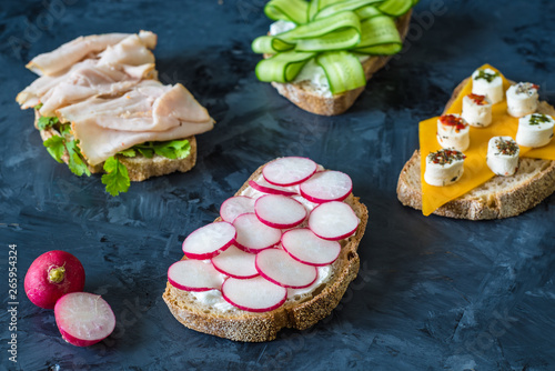 Healthy open sandwiches with vegetables , carrots , radish , cheddar cheese and turkey pastrami, cucumber on a wooden background , close up 