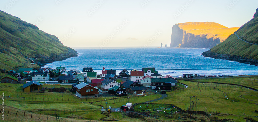 View of traditional nordic Tjornuvik village with colorful houses surrounded by green mountains in bay while sunrise. Stroymoy Island, Faroe Islands, Denmark Europe