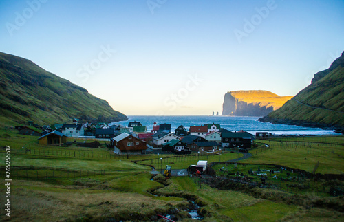 View of traditional nordic Tjornuvik village with colorful houses surrounded by green mountains in bay while sunrise. Stroymoy Island, Faroe Islands, Denmark Europe