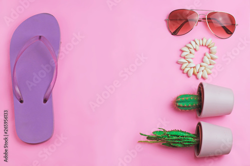  Beach purple flip flops, aviator sunglasses, seashell bracelet and succulent cacti cactus on a pink background. Summer vacation colorful travel beach flat lay with free copy space for text