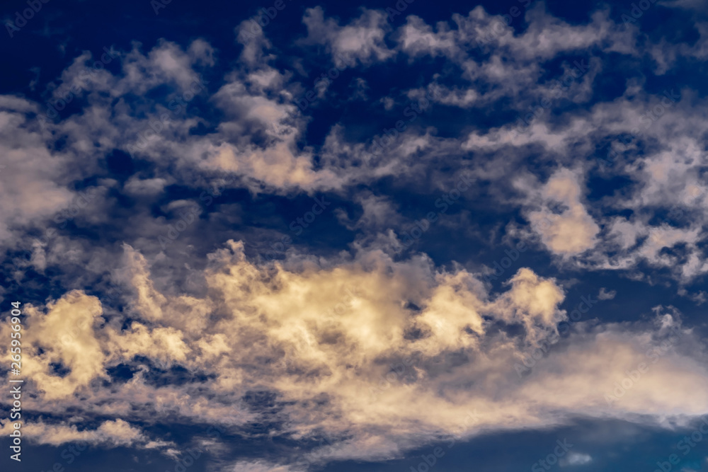 Obraz premium cumulus and cirrus clouds against the evening blue sunset sky