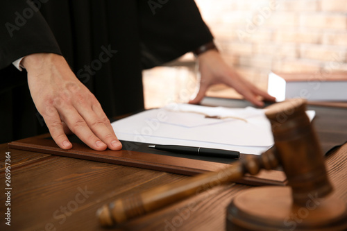 Judge with papers at table in office, closeup. Law and justice concept