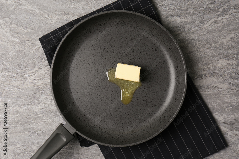 Frying pan with melting butter on grey table, top view Frying pan with melting butter on grey table, top view