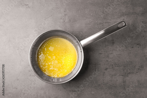 Saucepan with melting butter on grey table, top view photo