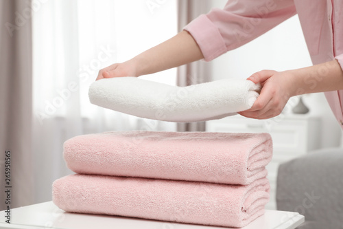 Woman stacking clean towels on table in room