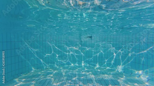 Someone diving into swimming pool at the background of waves texture on the pool bottom