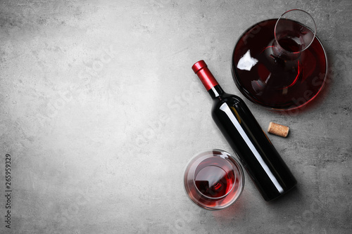 Decanter, glass and bottle with red wine on color background, flat lay. Space for text