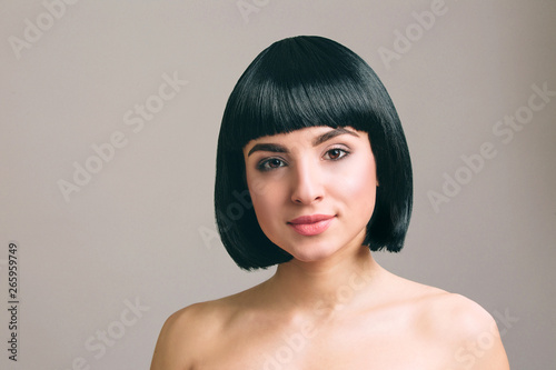 Young woman with black hair posing on camera. Isolated on light background. Bob haircut. Modern fashionable picture.